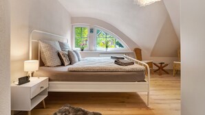 A bedroom with a bed, bedside table, lamp, window, and a view of greenery outside. - Holiday Home 'Im Grünen' with Private Terrace, Private Garden and Wi-Fi (Harsefeld)
