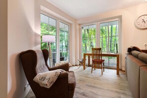 A cozy room with a brown leather chair, a wooden table with a chair, and a sofa.