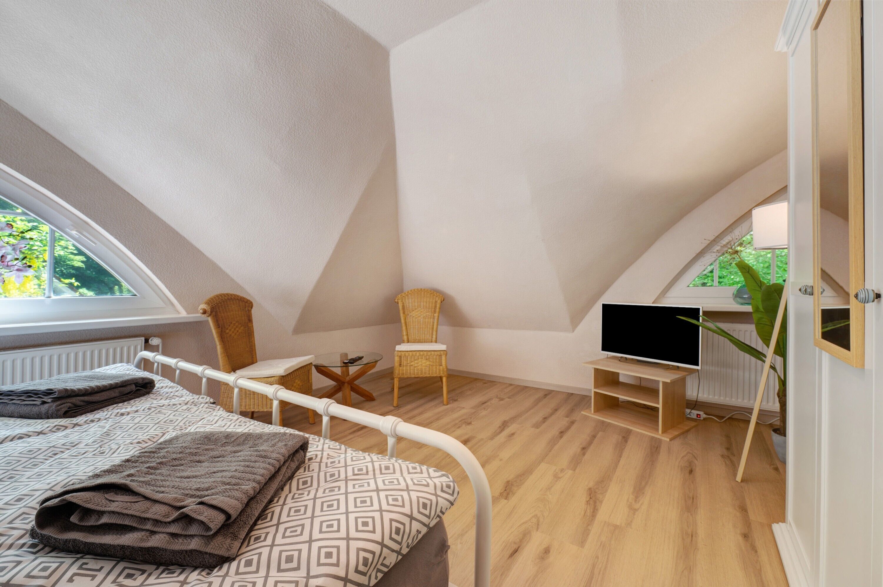 Een slaapkamer met een bed, een stoel, een televisie en een raam.