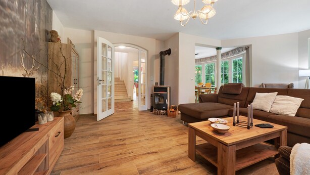 A living room with a wooden coffee table, a brown sofa, a TV, and a fireplace. - Holiday Home 'Im Grünen' with Private Terrace, Private Garden and Wi-Fi (Harsefeld)