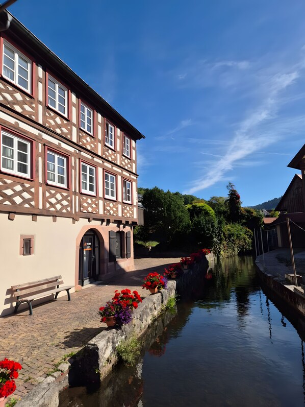 A traditional half-timbered building with a paved courtyard and a narrow water channel.