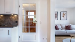 A modern kitchen with white cabinets, a black countertop, and a glass door leading to a dining area.
