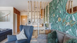 A modern living room with a sofa, armchair, and a decorative wall with leaf patterns. - Apartment 'Bootsmann Steinhude' with Private Terrace, Balcony and Wi-Fi (Wunstorf)