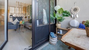 A modern living room with a sofa, a coffee table, a dining table, and a sliding glass door leading to another room. - Apartment 'Bootsmann Steinhude' with Private Terrace, Balcony and Wi-Fi (Wunstorf)