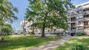 A multi-story residential building with balconies, a paved pathway, and a grassy area with trees. - Apartment 'Bootsmann Steinhude' with Private Terrace, Balcony and Wi-Fi (Wunstorf)