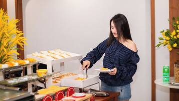 Montaje de bufé con diversos alimentos y una persona sirviendo.