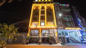 Un hotel con una entrada destacada, varios pisos y señalización iluminada.