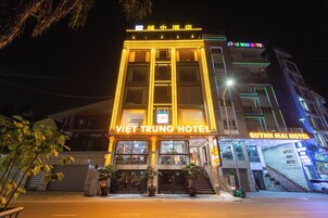 Un hotel con una entrada destacada, varios pisos y señalización iluminada.