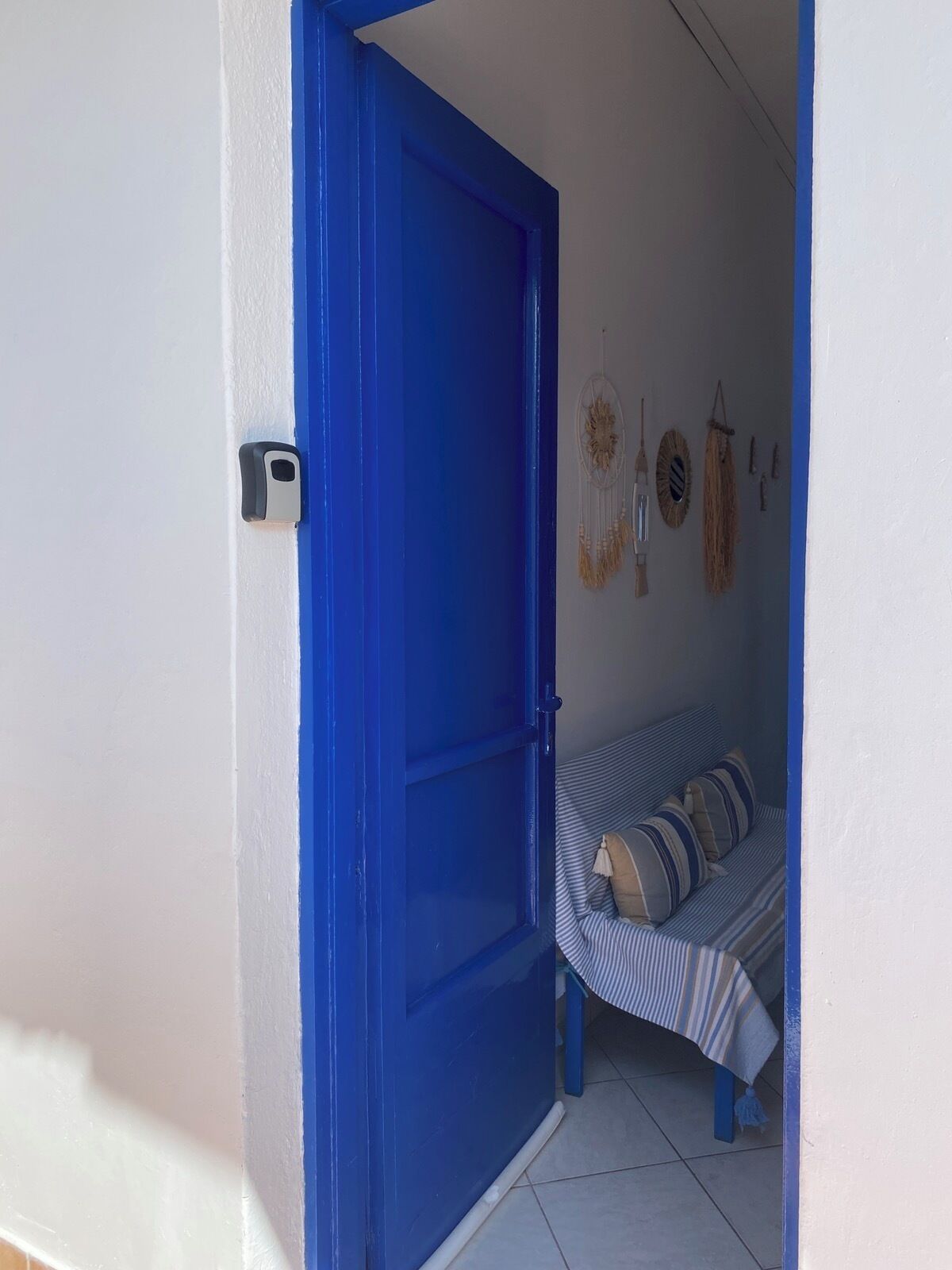 Una stanza con una porta blu, un letto con lenzuola a righe e decorazioni alle pareti.