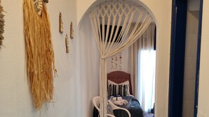 Un pasillo con un tapiz de macramé, un rug decorativo y una cama con dosel al fondo.