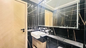 Un baño moderno con un espejo grande, un lavabo blanco y una encimera negra.