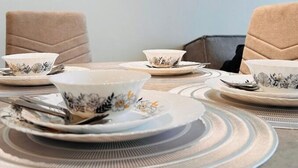 Una mesa de comedor dispuesta con platos, tazones y cubiertos.