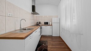 A modern kitchen with white cabinets, a wooden countertop, stainless steel appliances, and a wooden floor.