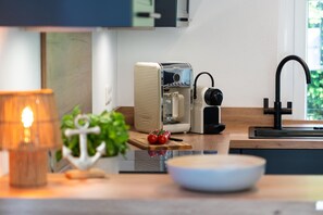 A modern kitchen with a coffee maker, a sink, and a bowl on the counter.