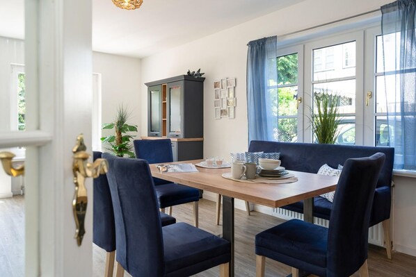 A dining area with a wooden table, blue upholstered chairs, and a dark-colored cabinet.