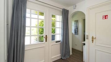 A hallway with a white door, grey curtains, and a window with blinds.