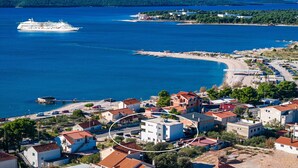 Une ville côtière avec un navire de croisière en mer, une plage et des immeubles résidentiels.
