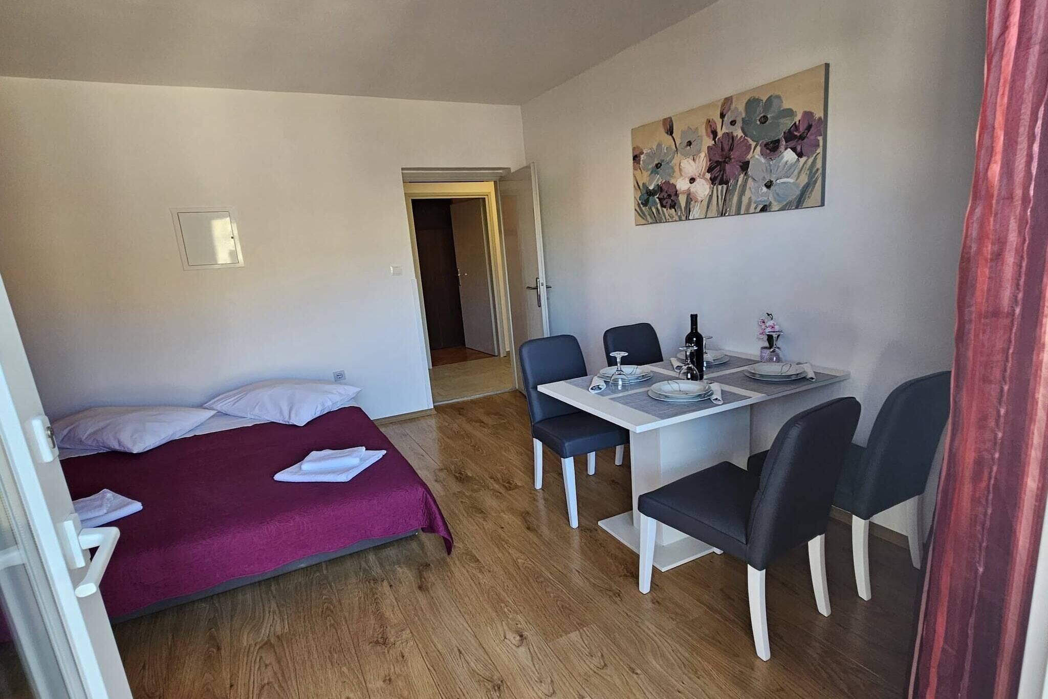 Habitació amb un llit, taula de menjador i cadires, i un quadre penjat a la paret.