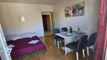 Habitació amb un llit, taula de menjador i cadires, i un quadre penjat a la paret.