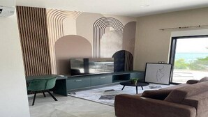 Ein modernes Wohnzimmer mit einer Couch, einem Esstisch mit Stühlen, einem Fernseher und einem Bild an der Wand.