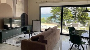 Ein modernes Wohnzimmer mit Sofa, Fernseher und Essbereich mit Tisch und Stühlen.