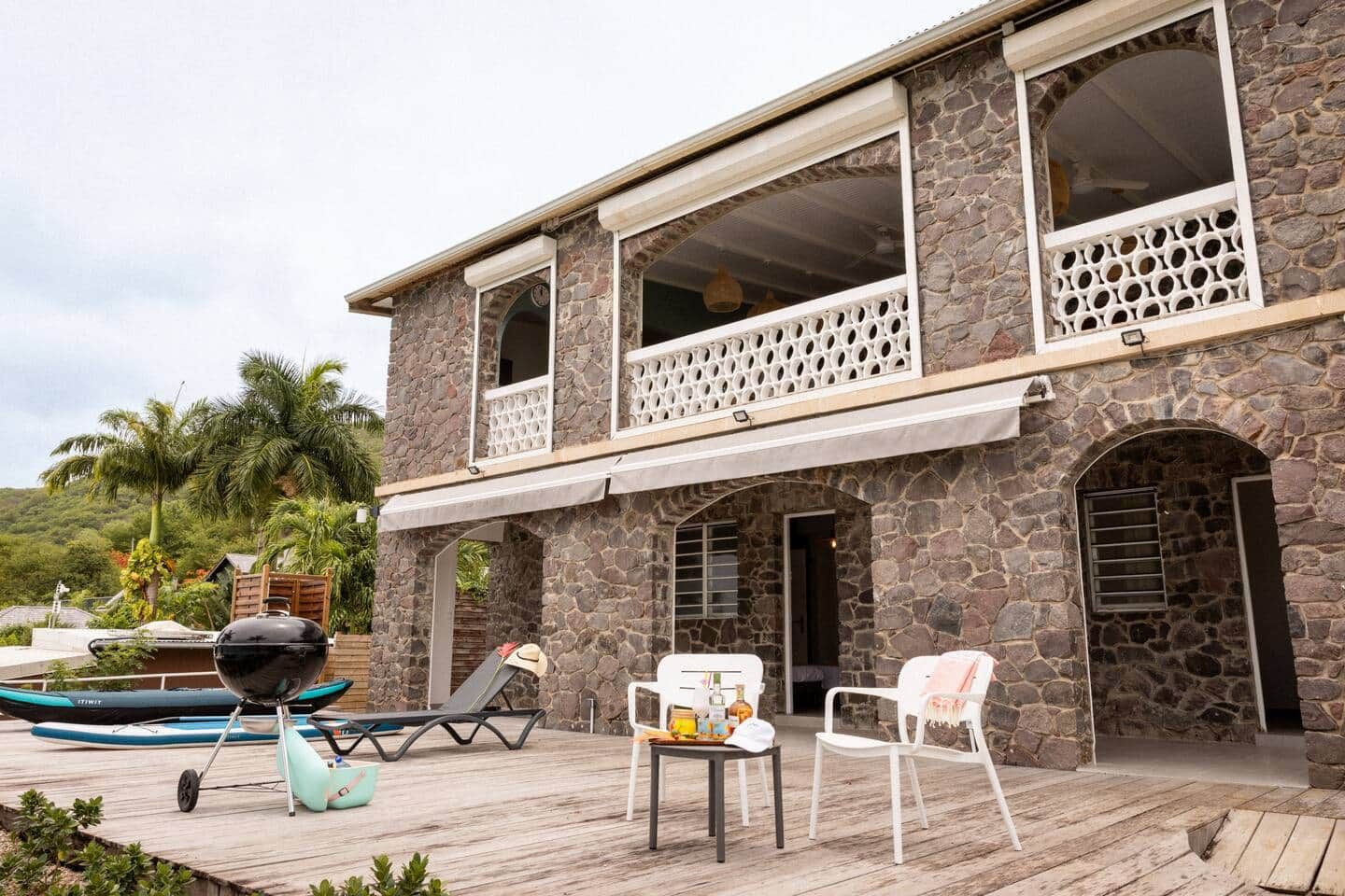 A stone building with a balcony, outdoor seating, and a grill.