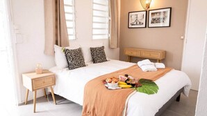 Una habitación de hotel ordenada con una cama, una mesita de noche y un pequeño armario.
