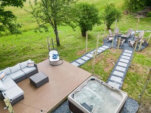 Un jacuzzi con cubierta de madera, asientos exteriores y un sendero de piedra.