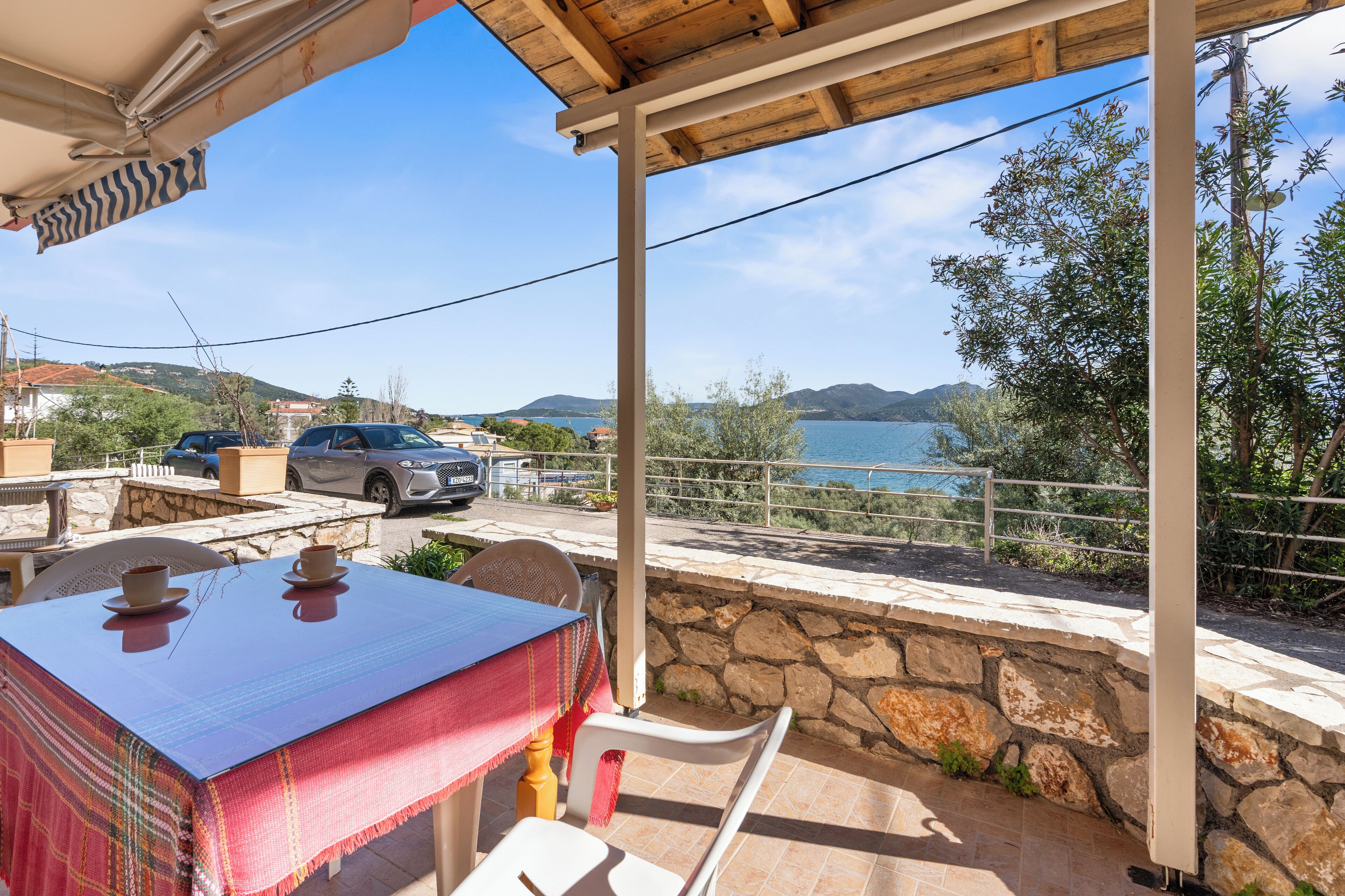Un espace extérieur aménagé, abrité et doté d’une table et de chaises, offrant une vue panoramique sur un lac et des montagnes.