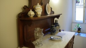 A kitchen counter with antique porcelain dishes, a glass pitcher, and a vase.