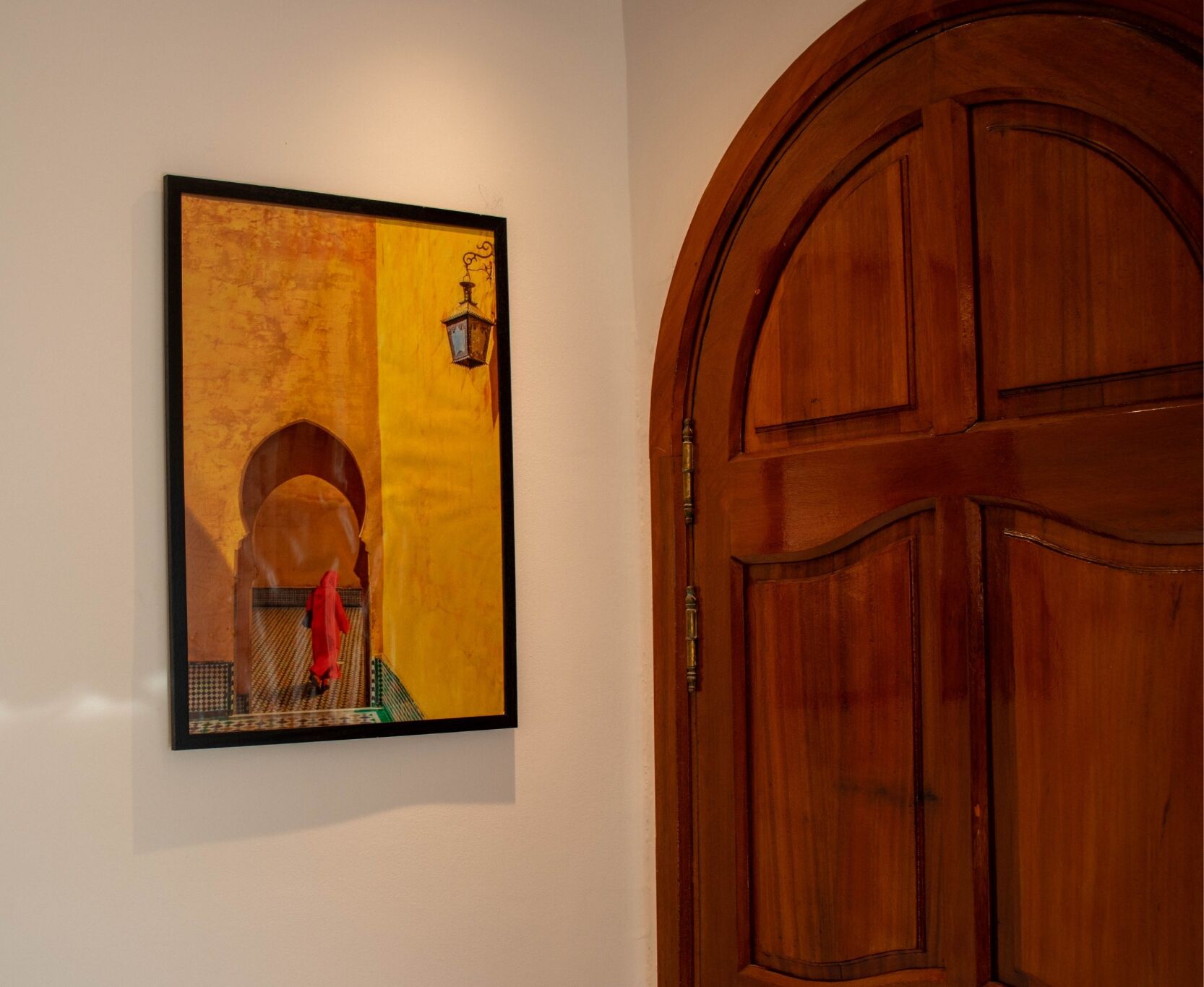Una obra de arte enmarco en una pared junto a una puerta de madera.