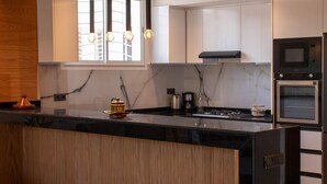 A modern kitchen with a black countertop, white cabinets, a built-in oven, and a microwave. - ZAYANE HOMES RABAT BEACH (Harhoura)