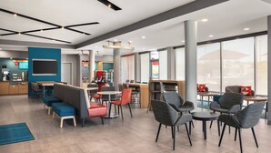 A modern hotel lobby with seating areas, a reception desk, and large windows.