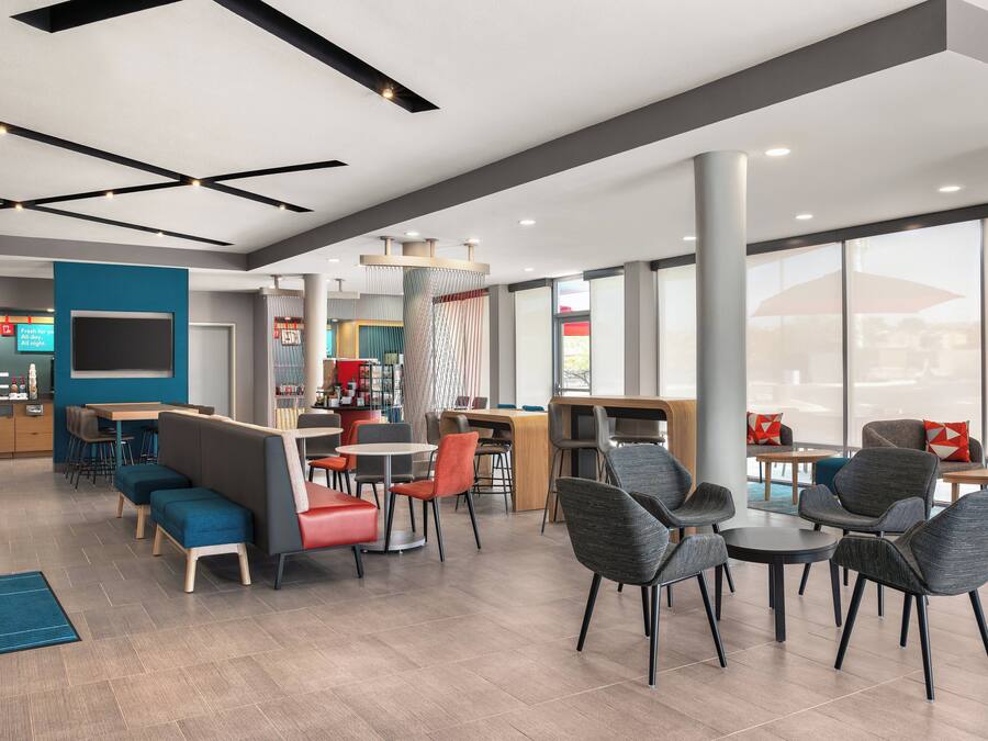 A modern hotel lobby with seating areas, a reception desk, and large windows.
