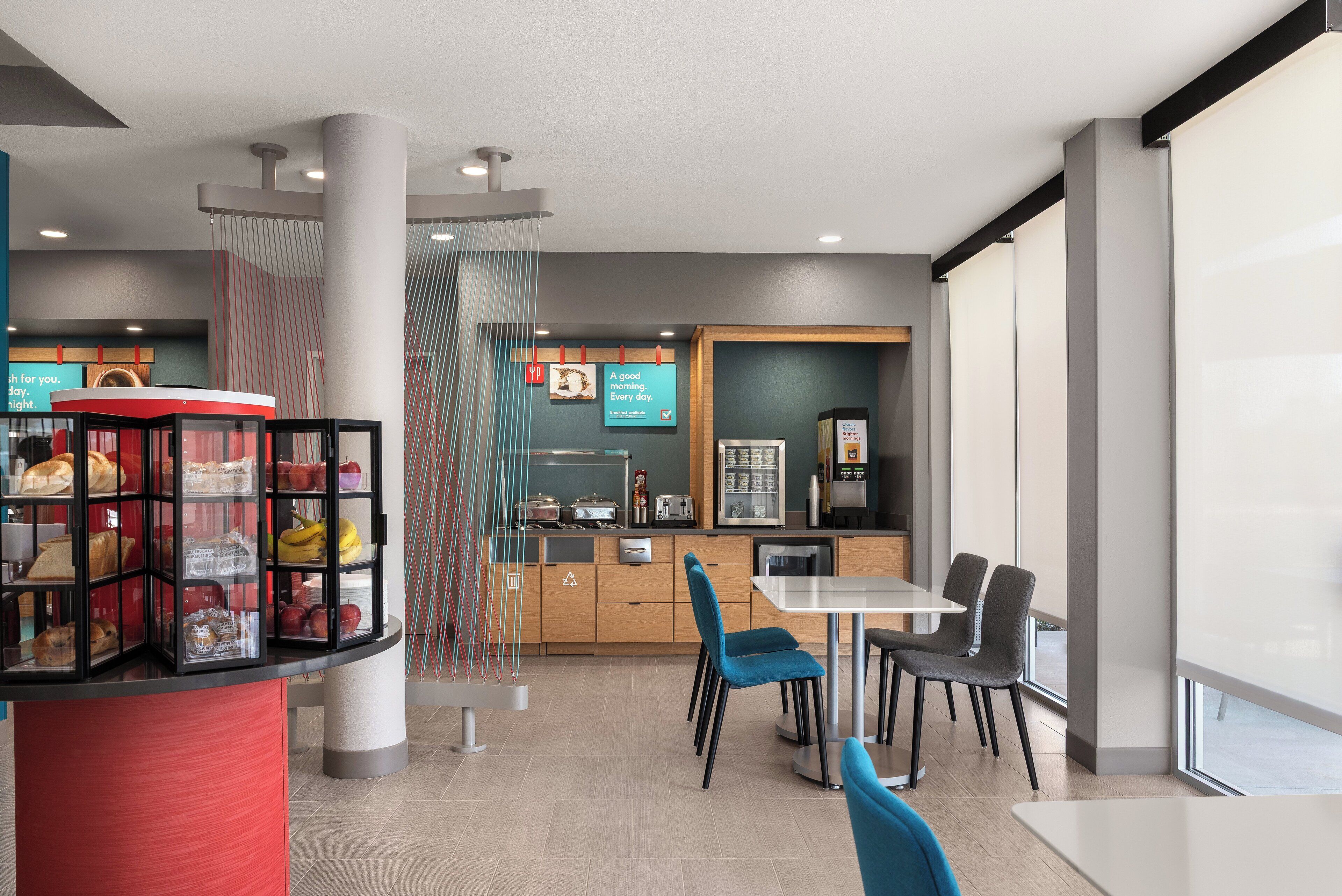 A modern cafe interior with a seating area, a display case with pastries, and a breakfast bar.