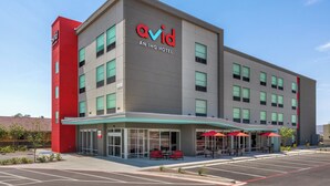 A modern building with a red and grey facade, labeled as 'avid an IHG hotel'.