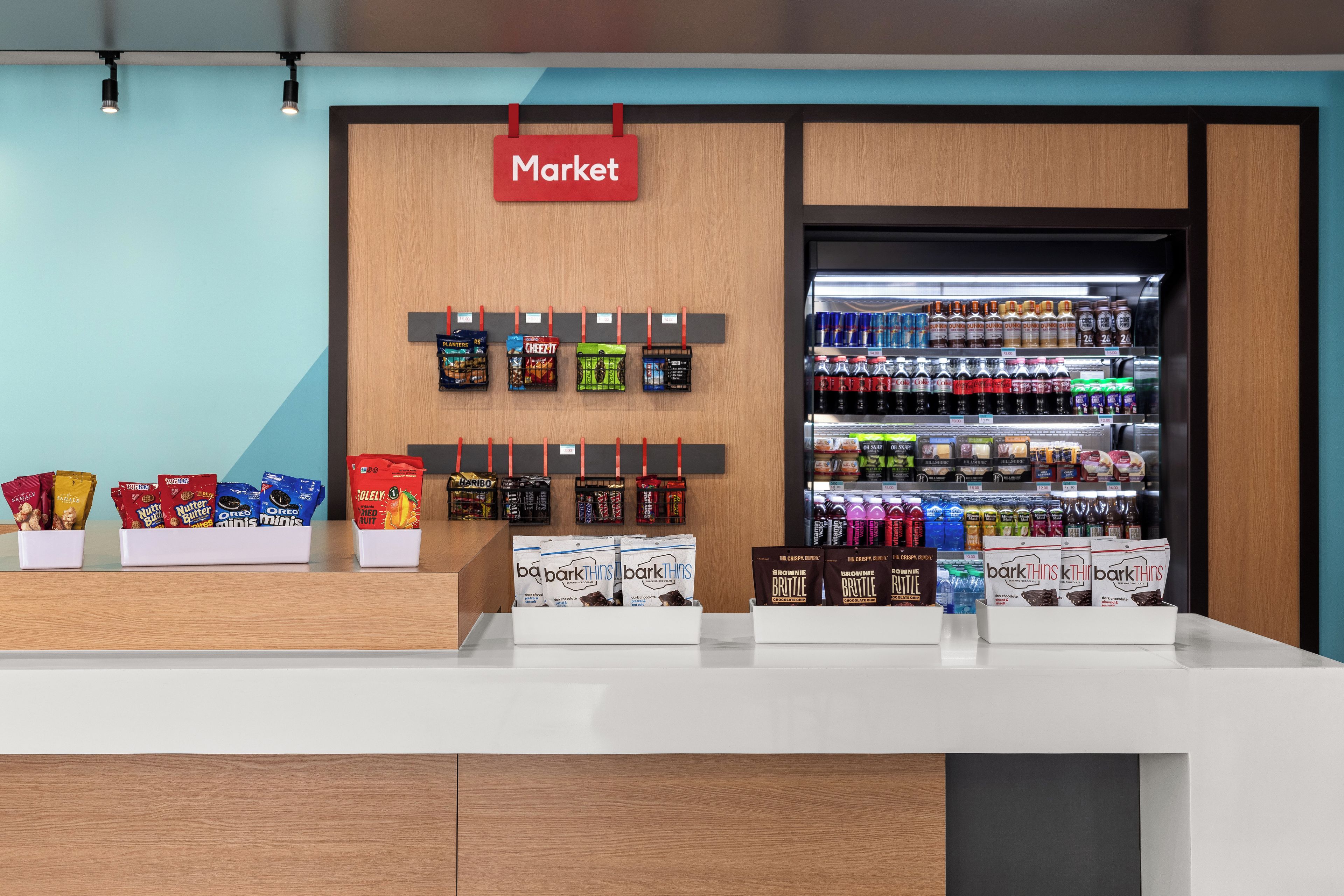A market area with snack displays and a refrigerated beverage section.