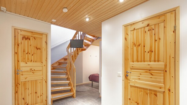 A wooden staircase with a TV mounted on the wall above it, leading to an upper level. - 3BR Holiday Apt. with Sauna (Kittilä)