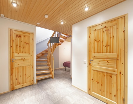 A wooden staircase with a TV mounted on the wall above it, leading to an upper level.