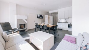 A modern living room with a fireplace, a dining area, and a kitchen. - 3BR Holiday Apt. with Sauna (Kittilä)