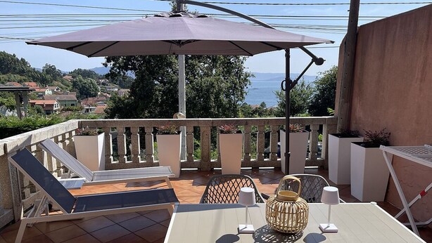 Un balcon équipé d’une table, de chaises, d’une chaise longue et d’un grand parasol.