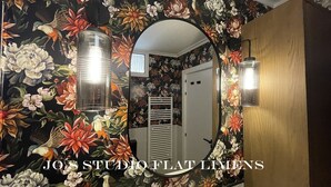 Une salle de bain avec un papier peint à motifs floraux, un miroir et deux appliques murales.