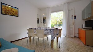 Un coin repas avec une table dressée pour quatre personnes, un canapé bleu et un espace cuisine équipé d’un four à micro-ondes.