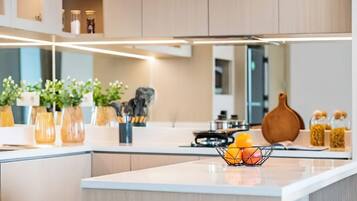 A modern kitchen with a central island, built-in cabinets, and a variety of decorative items including plants and kitchenware.