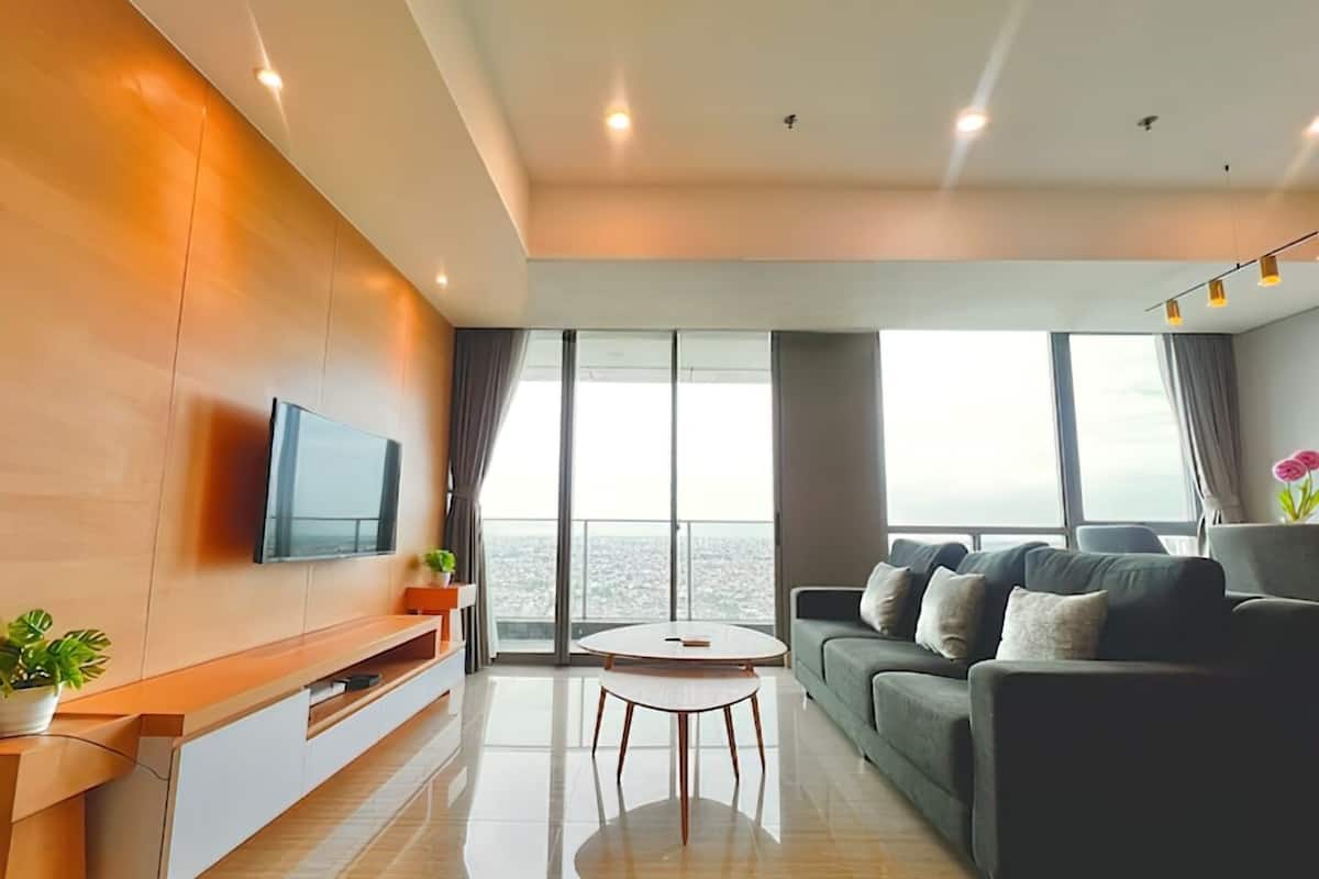 A modern living room with a large window, a flat-screen TV, a sofa, a coffee table, and a plant.