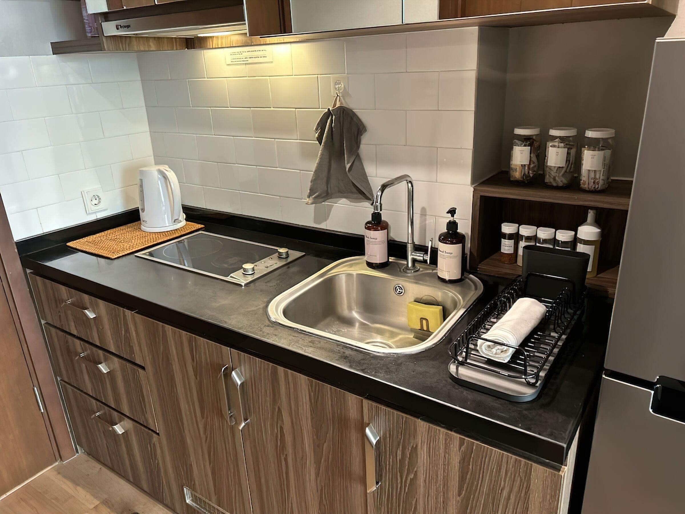 Una cocina moderna con un lavamanos de acero inoxidable, una tetera y varios utensilios de cocina.