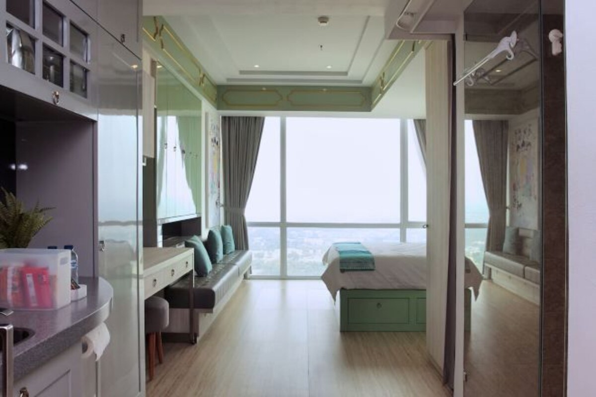 Un dormitorio moderno con un ventanal grande, una cama, un escritorio y una zona de estar.