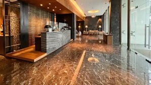 Una hall moderna con pavimento in marmo, una reception e un'area salotto con divani.