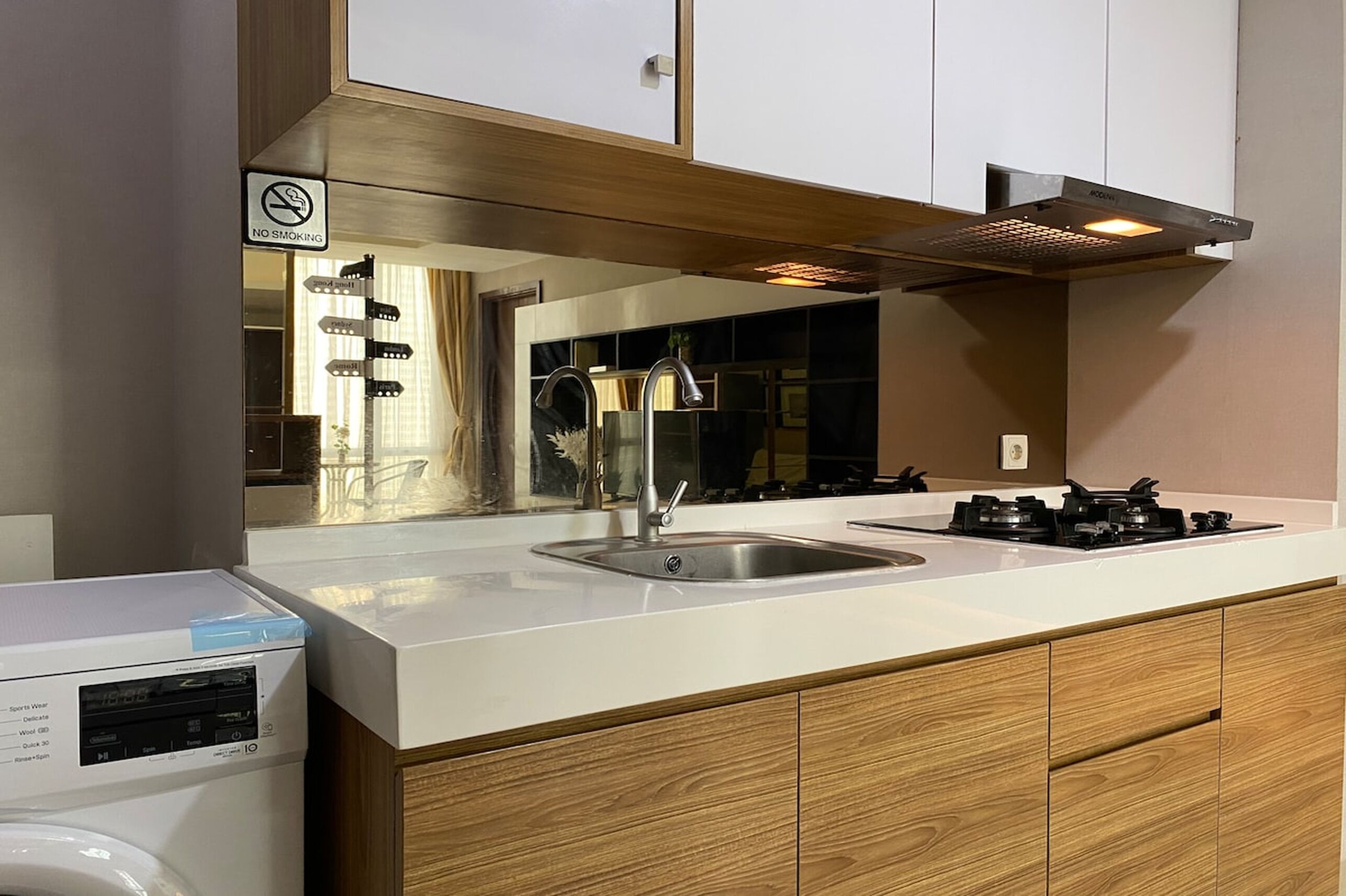 A modern kitchen with a stainless steel sink, a built-in stove, and wooden cabinets.