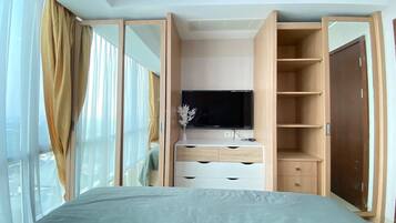 A bedroom with a bed, a TV, a wardrobe, and a window with curtains.